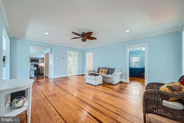 living area with crown molding, visible vents, baseboards, and wood finished floors