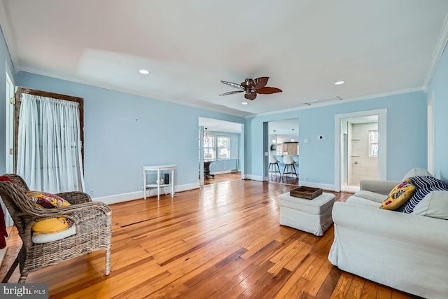 living area with visible vents, crown molding, baseboards, and wood finished floors