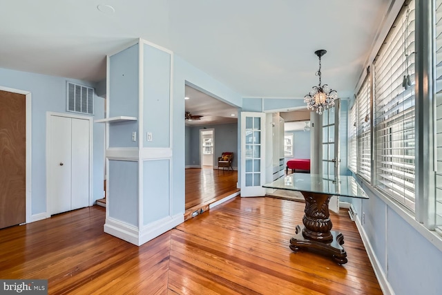 dining space featuring french doors, wood finished floors, visible vents, and an inviting chandelier