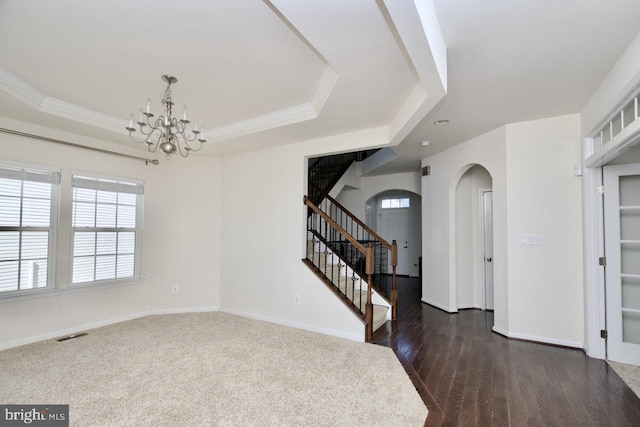 foyer entrance with visible vents, baseboards, stairway, a raised ceiling, and an inviting chandelier