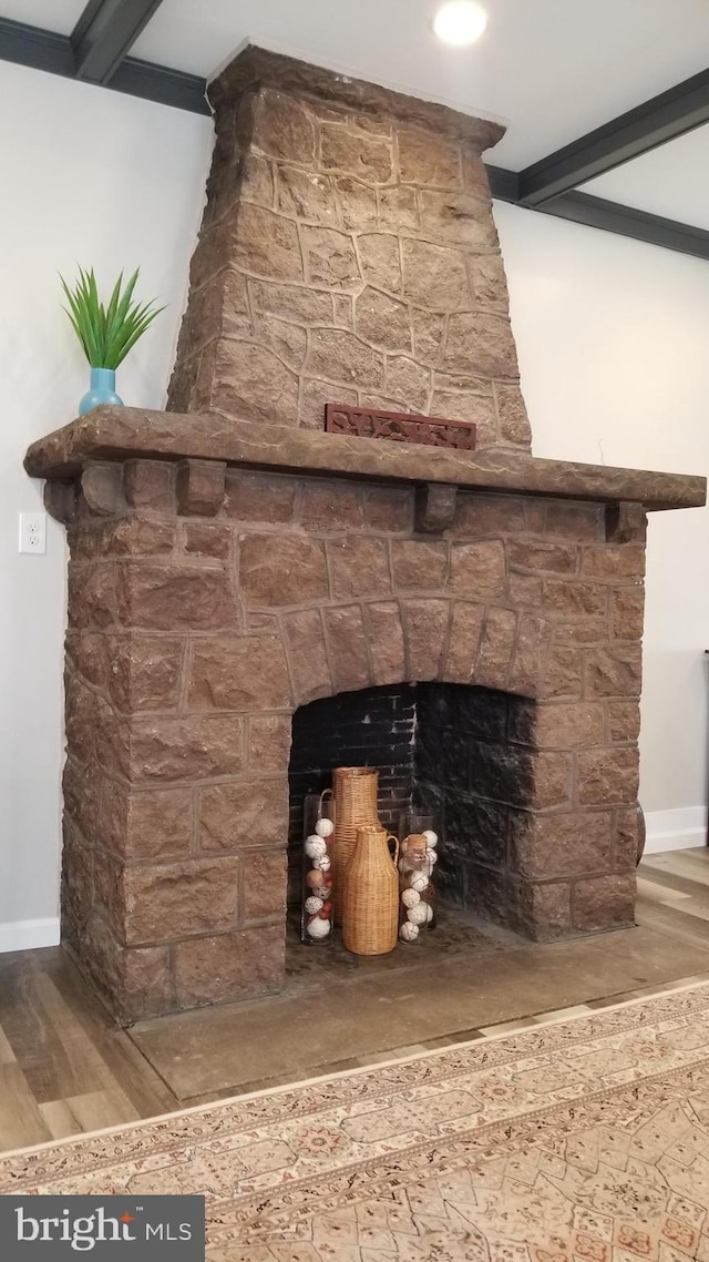 interior details with a fireplace, wood finished floors, and beamed ceiling