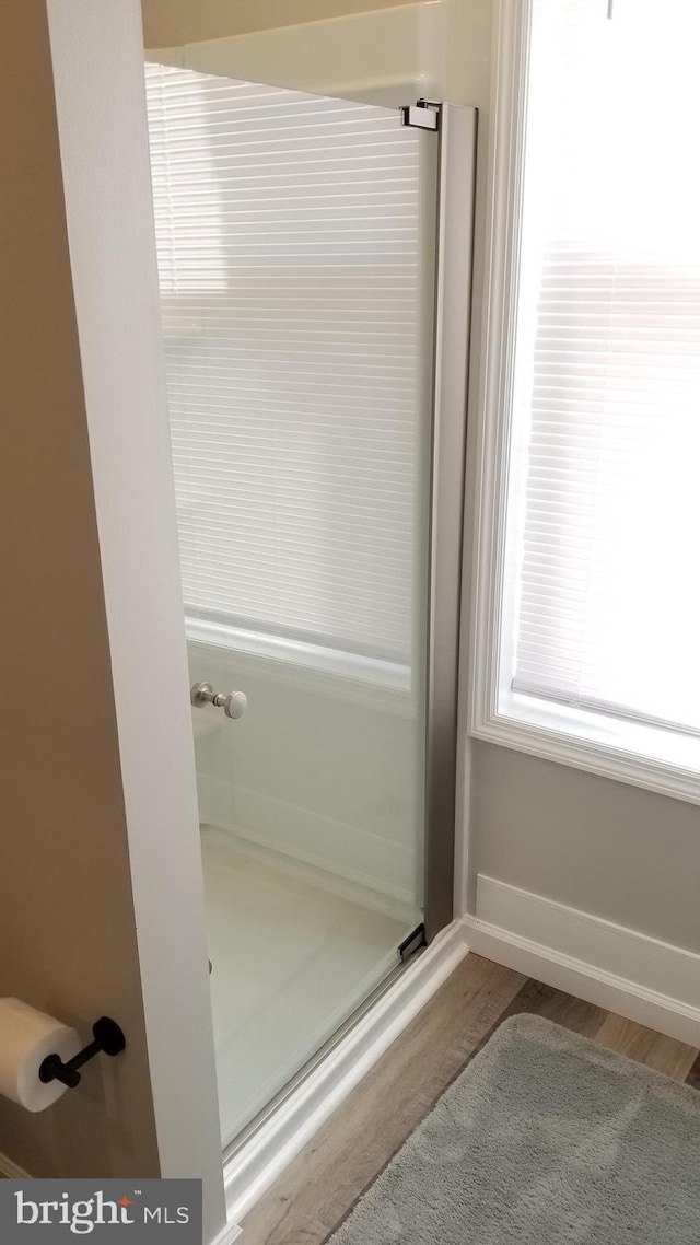 full bath with a shower stall, baseboards, and wood finished floors