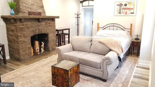 bedroom featuring a fireplace, baseboards, and wood finished floors