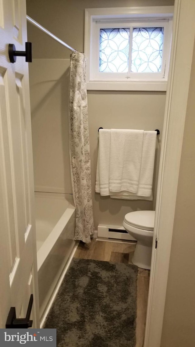 bathroom with a healthy amount of sunlight, a baseboard heating unit, toilet, and wood finished floors