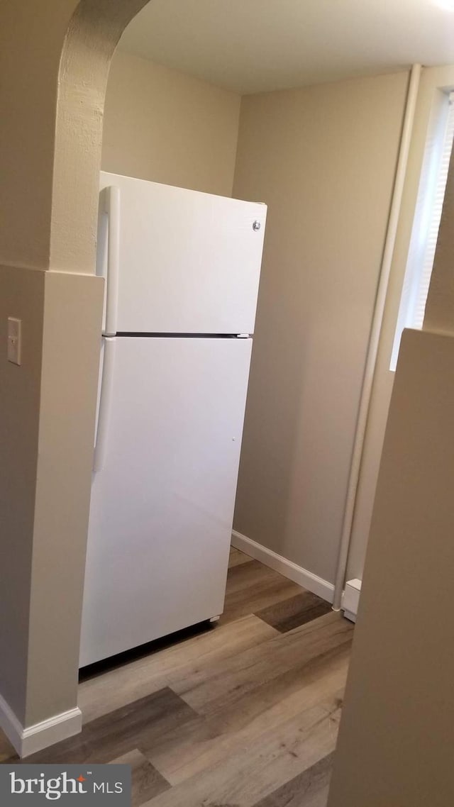 kitchen featuring freestanding refrigerator, baseboards, and wood finished floors