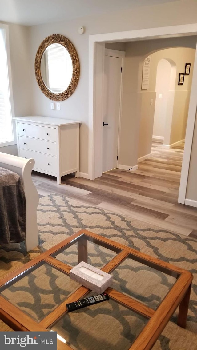 bedroom featuring light wood-style floors, arched walkways, and baseboards