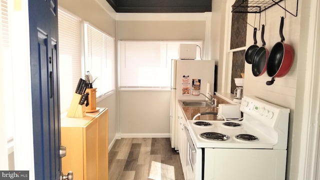 kitchen with baseboards, wood finished floors, white electric range, white cabinetry, and a sink