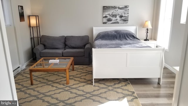 bedroom featuring a baseboard radiator, wood finished floors, and baseboards