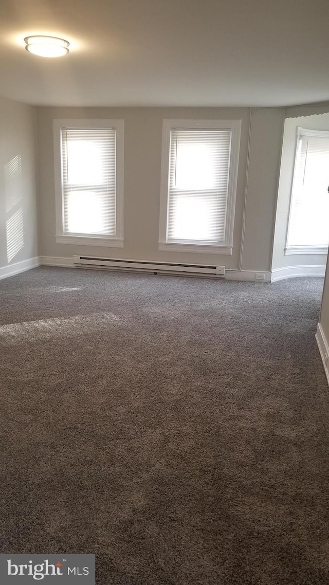 carpeted spare room with baseboards, plenty of natural light, and baseboard heating