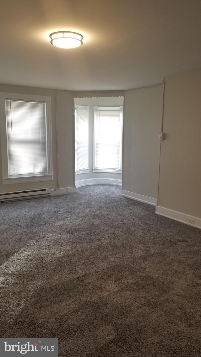 carpeted empty room featuring a baseboard radiator and baseboards