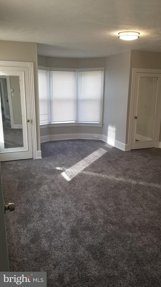 carpeted spare room with a textured ceiling and baseboards