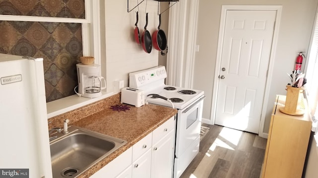 kitchen with white electric range, water heater, white cabinetry, a sink, and wood finished floors