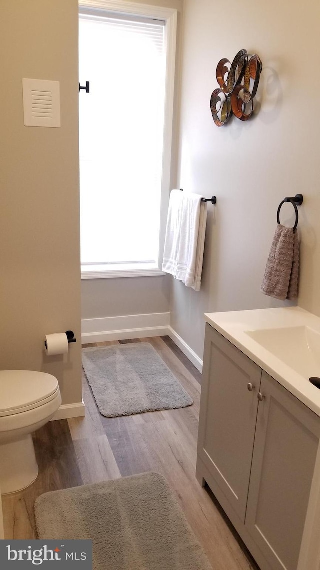 bathroom with vanity, wood finished floors, toilet, and baseboards