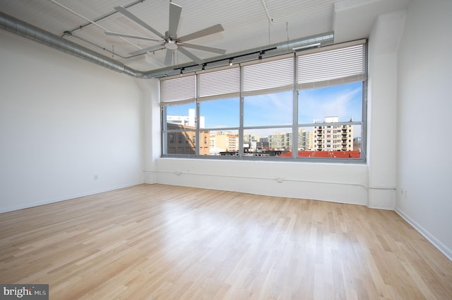 unfurnished room with a wealth of natural light, a view of city, and wood finished floors