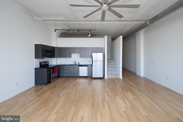 kitchen featuring dishwashing machine, freestanding refrigerator, stainless steel range with electric cooktop, black microwave, and a sink