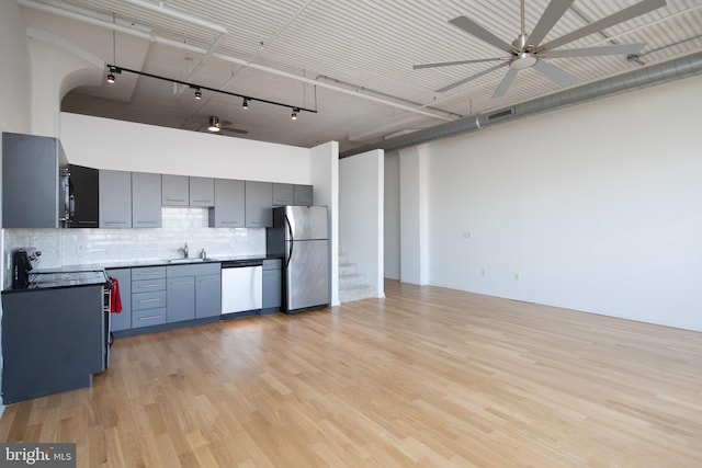 kitchen with stainless steel appliances, a sink, a ceiling fan, gray cabinets, and tasteful backsplash