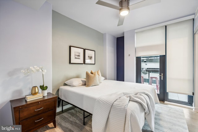 bedroom featuring light wood finished floors, expansive windows, and a ceiling fan