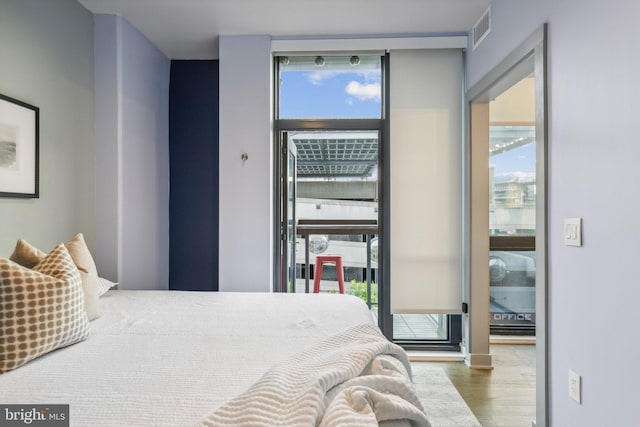 bedroom featuring visible vents, multiple windows, floor to ceiling windows, and wood finished floors