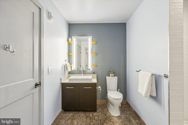 bathroom featuring toilet, vanity, and baseboards