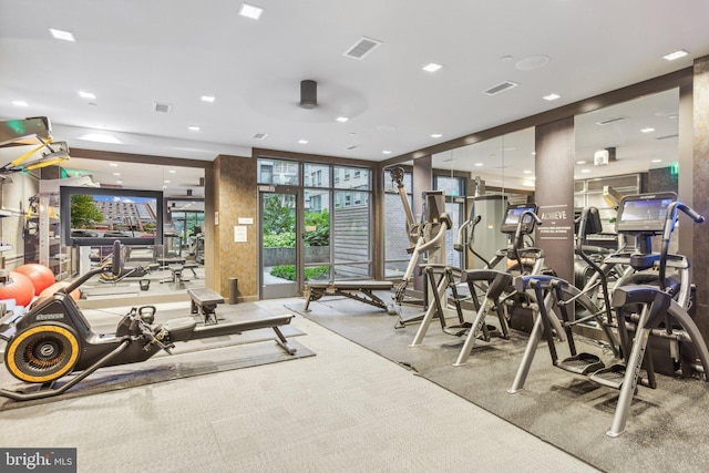 gym with expansive windows, carpet floors, and visible vents