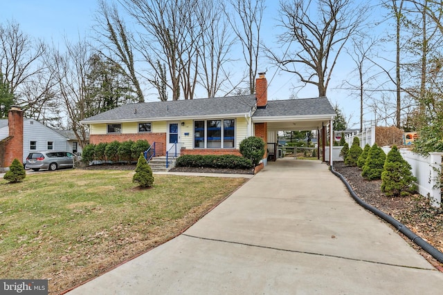 ranch-style home featuring brick siding, concrete driveway, a front yard, fence, and an attached carport