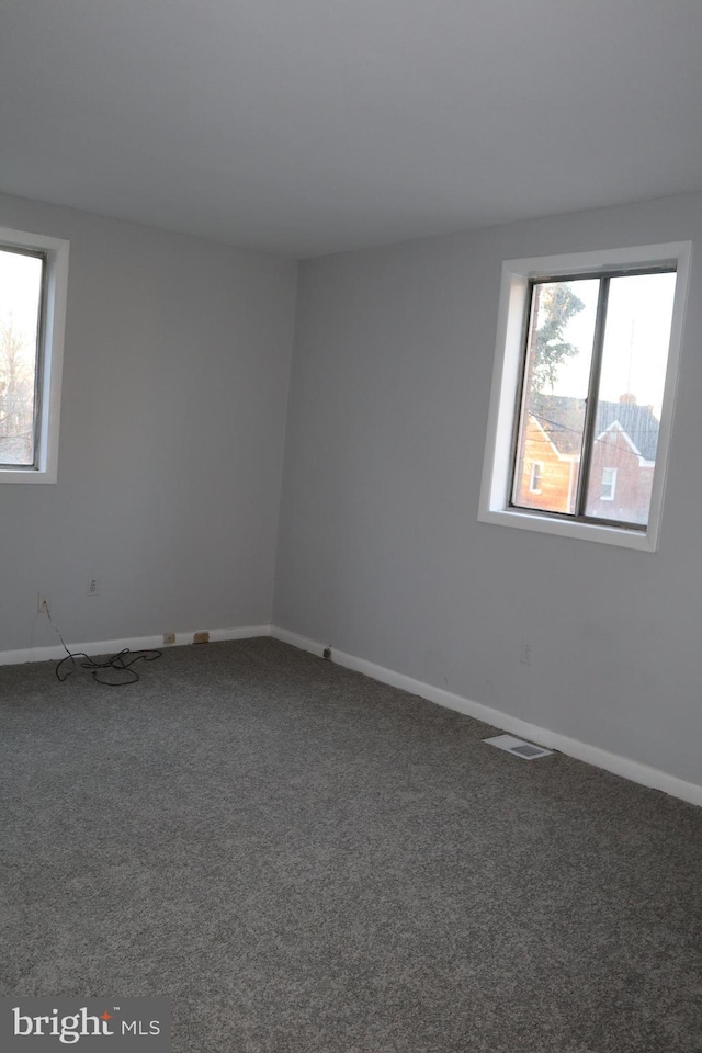 spare room with carpet, visible vents, and baseboards