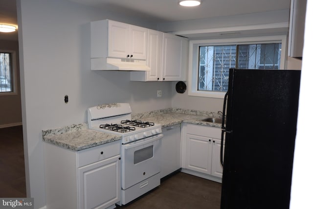 kitchen with light stone counters, under cabinet range hood, white cabinets, freestanding refrigerator, and gas range gas stove