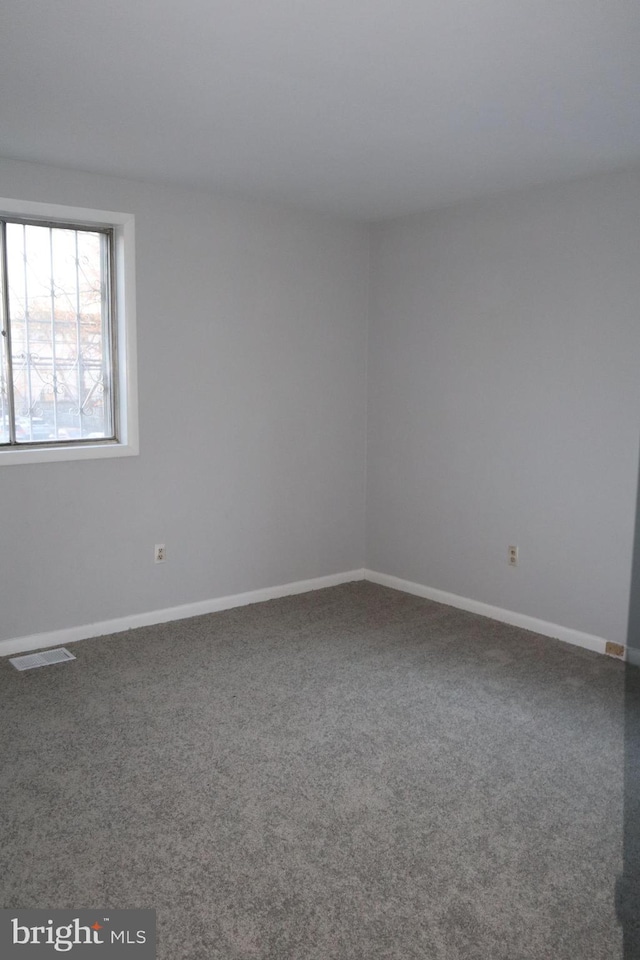 spare room featuring carpet flooring, visible vents, and baseboards