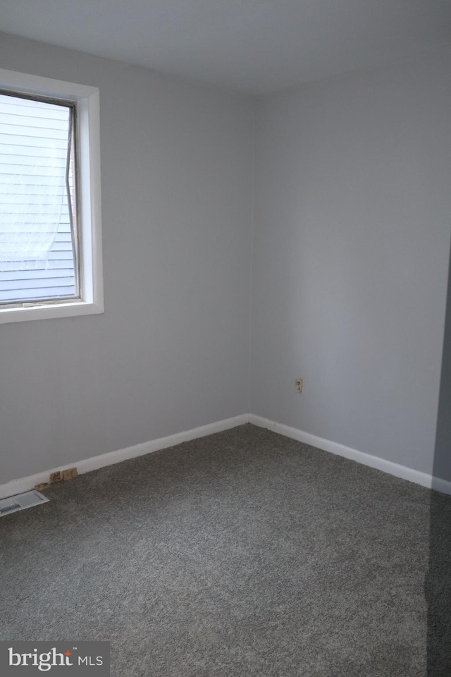 unfurnished room with carpet, visible vents, and baseboards