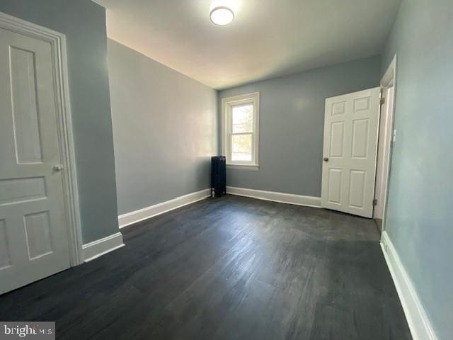 spare room with dark wood-type flooring and baseboards