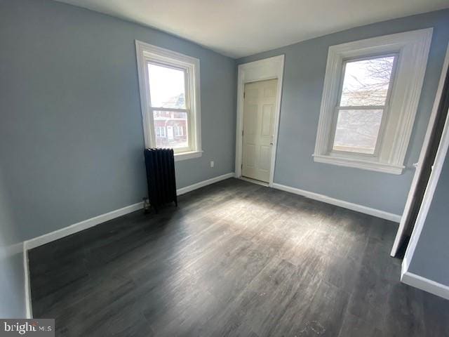 unfurnished bedroom featuring radiator heating unit, baseboards, and dark wood-style flooring