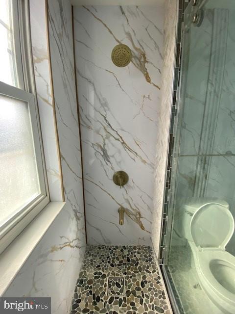 bathroom with a healthy amount of sunlight and a marble finish shower