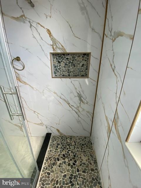 bathroom with a marble finish shower and stone finish floor