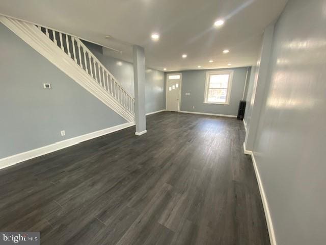 unfurnished living room with dark wood-style floors, recessed lighting, baseboards, and stairs