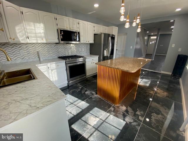 kitchen featuring white cabinets, a kitchen island, marble finish floor, stainless steel appliances, and a sink