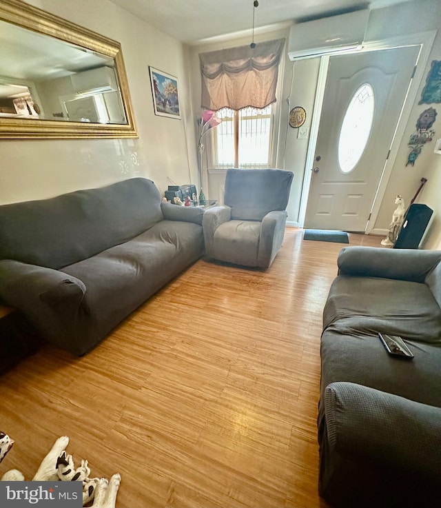 living room with light wood-style floors and a wall unit AC