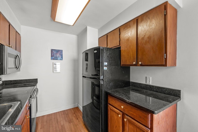 kitchen featuring freestanding refrigerator, stainless steel microwave, brown cabinetry, and light wood-style floors