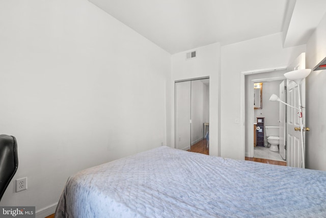 bedroom with light wood finished floors, visible vents, and baseboards