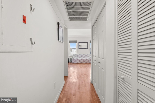 corridor featuring light wood-type flooring, visible vents, and baseboards