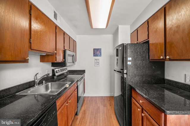 kitchen with light wood-style flooring, a sink, visible vents, brown cabinets, and black appliances