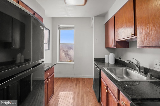 kitchen with black appliances, light wood finished floors, brown cabinetry, and a sink