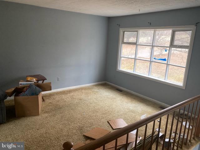 interior space with visible vents, stairs, baseboards, and a textured ceiling