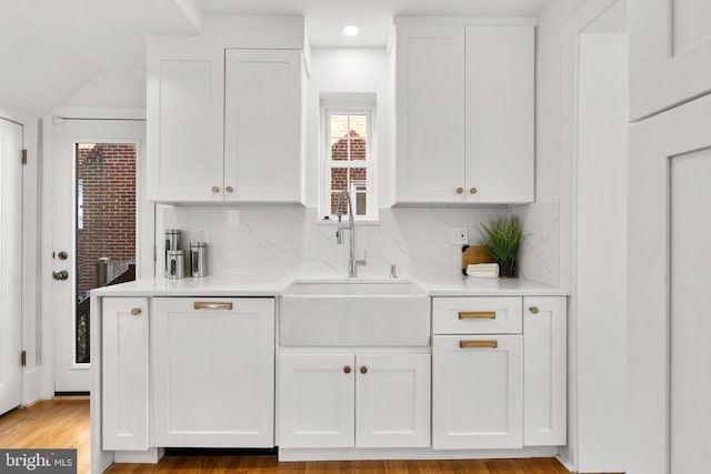 kitchen with light countertops, a sink, white cabinetry, and decorative backsplash