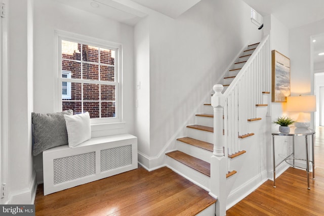 staircase featuring radiator heating unit, baseboards, and wood finished floors