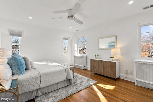 bedroom with radiator heating unit, visible vents, and wood finished floors