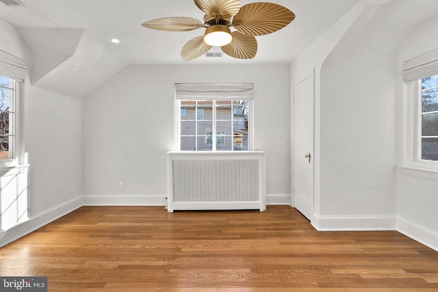 additional living space with lofted ceiling, radiator heating unit, light wood-type flooring, and baseboards