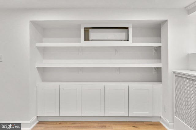 interior space featuring a wall mounted air conditioner, baseboards, and wood finished floors