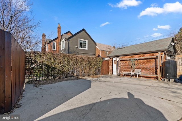 exterior space featuring a patio area, a chimney, fence, and brick siding