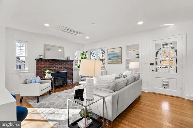 living area with recessed lighting, wood finished floors, visible vents, and built in features