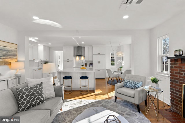 living room with visible vents, baseboards, wood finished floors, and recessed lighting